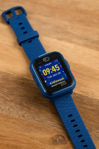VTech Kidizoom Smartwatch DX3 with blue strap on wooden surface – playful display showing time and date